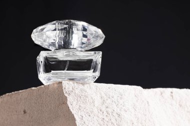 Gri tuğla üzerinde şeffaf bir koku şişesi.