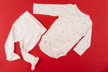 Kırmızı arkaplanda bebek kıyafetleri.