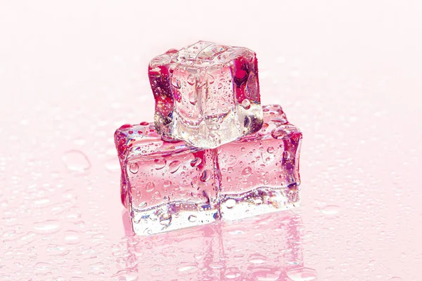 Fozen kostki lodu na mokrym różowym tle — Zdjęcie stockowe