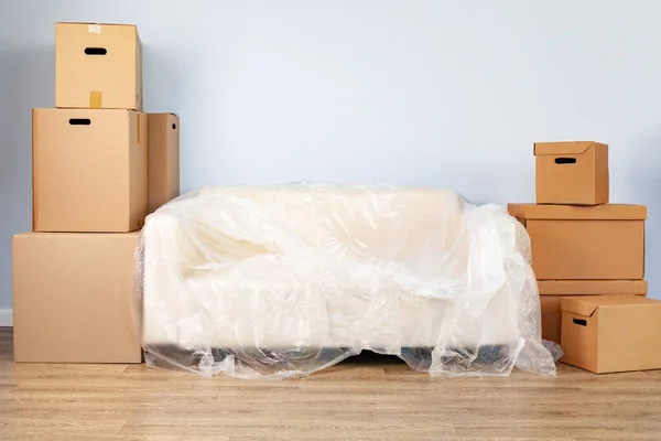 Упаковані побутові речі в коробки і упакований диван для переміщення — стокове фото