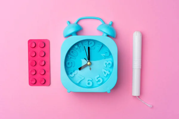 Relógio de alarme azul, almofada higiénica feminina e tampão, vista superior — Fotografia de Stock