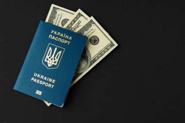 Siyah arka planda Amerikan doları banknotları olan Ukrayna pasaportu