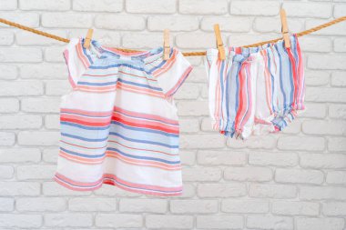 Şirin bebek renkli giysiler bir ipe asılmış.