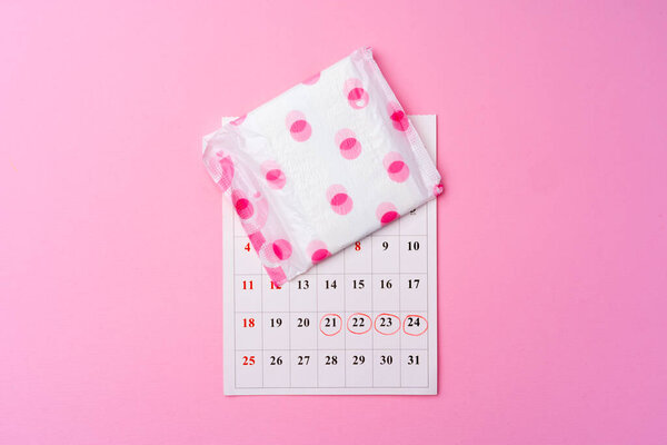 Страница календаря и женская гигиеническая прокладка на розовом фоне