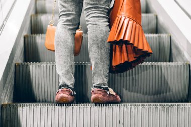 Bir alışveriş merkezinin yürüyen merdiveninde duran bacaklar.