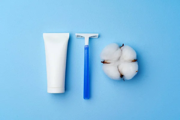 Crema de afeitar y afeitadora desechable sobre fondo azul — Foto de Stock