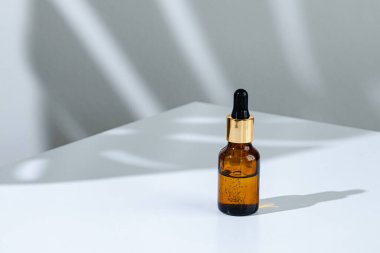 Beyaz arka planda tropik çiçeğin gölgesi olan pipetli kozmetik şişesinin yaratıcı fotoğrafı