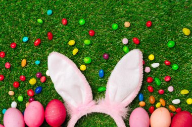 Renkli yumurtalar ve çimlerin üzerinde canlı şekerler. Paskalya Kompozisyonu