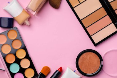 Cilt makyaj ürünleri ve pembe arka planda fırça