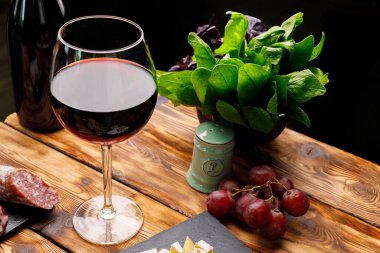 Bir bardak şarap ve ahşap masada doğranmış et.