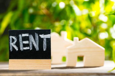 Ahşap ev minyatür ve yeşillik arka planında siyah kira etiketi