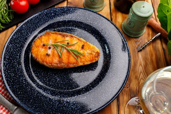 Стейк из лосося на синей тарелке на деревянном столе — стоковое фото