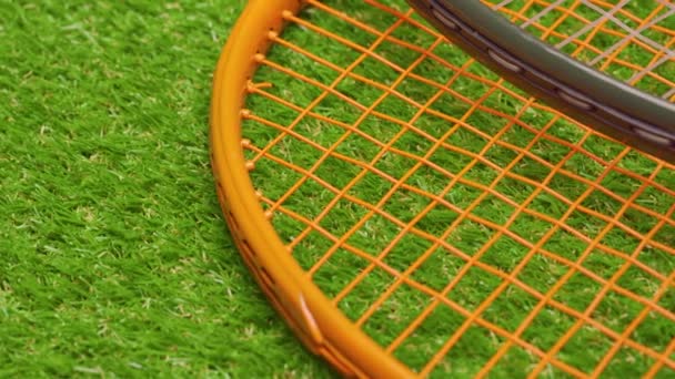 Дві тенісні ракетки, що лежать на фоні трави крупним планом — стокове відео
