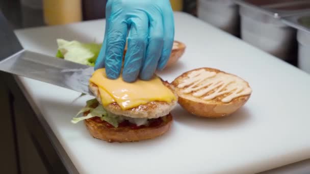 Cozinheiro profissional dobra um hambúrguer a bordo na cozinha do restaurante de perto — Vídeo de Stock