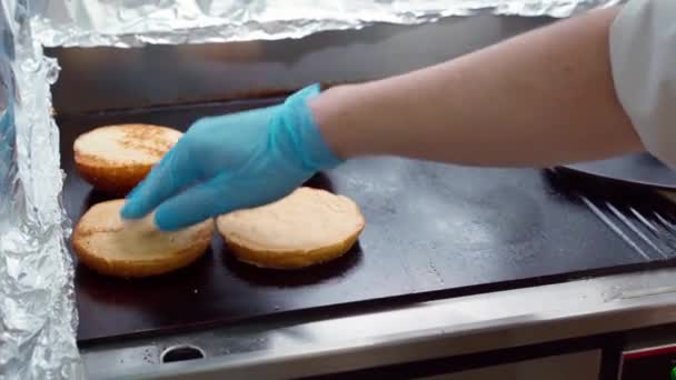 Bollos de hamburguesas calentándose en parrilla profesional en cocina industrial — Vídeo de stock