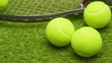 Yeşil çimlerde tenis topları ve raket yakın plan