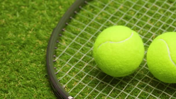 Piłki tenisowe i rakieta na zielonym tle trawy zbliżyć — Wideo stockowe