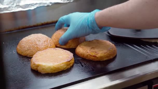 Bollos de hamburguesas calentándose en parrilla profesional en cocina industrial — Vídeo de stock