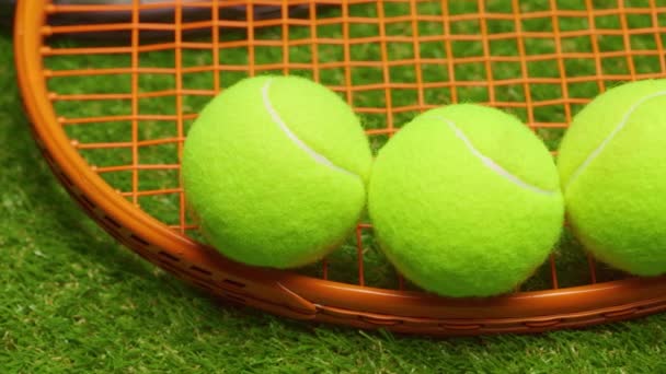 Pelotas de tenis y raqueta sobre hierba verde fondo de cerca — Vídeo de stock