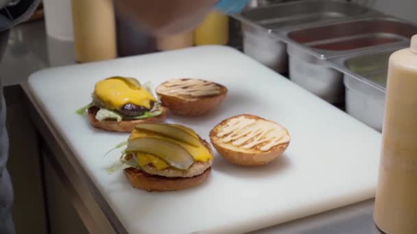 Profesionální kuchař složí burger na palubě v restauraci kuchyně zblízka — Stock video