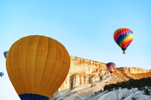 Büyük beyaz dağların yakınında açık gökyüzünde uçan renkli hava balonları — Stok fotoğraf