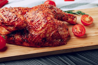 Ahşap kesme tahtasının üzerinde ızgara tavuğun yarısı.