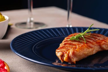 Mavi tabakta servis edilen ızgara biftek.