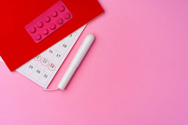 Takvim sayfasında tampon ve pembe arka planda haplar var.