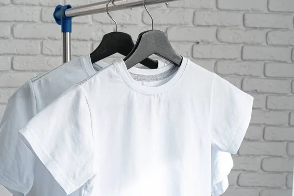 Camiseta blanca colgando de la percha contra la pared de ladrillo — Foto de Stock