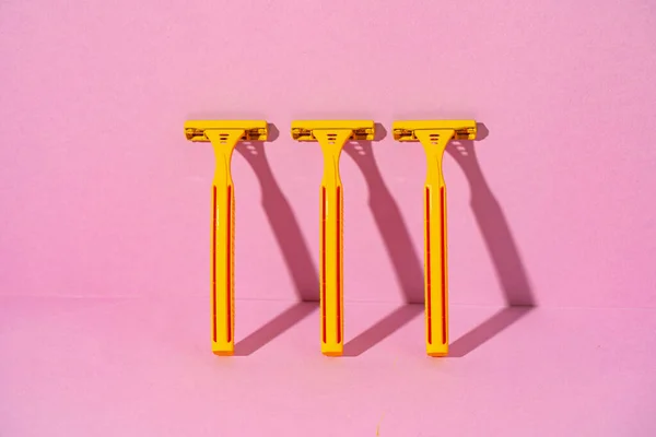 Žluté jednorázové holicí strojky na růžovém pozadí, studio shot — Stock fotografie