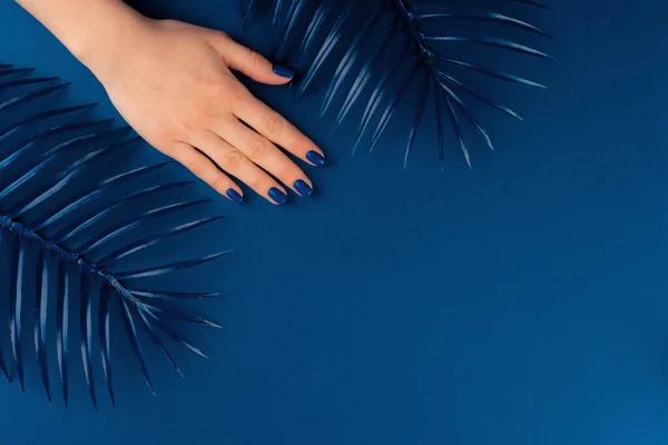 Manos femeninas con manicura de color azul clásico sobre fondo azul — Foto de Stock