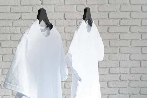 Weißes T-Shirt hängt an Kleiderbügel an Ziegelwand — Stockfoto