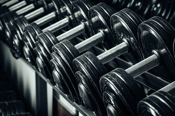 Sports equipment in gym. Dumbbells of different weight close up — Stock Photo, Image