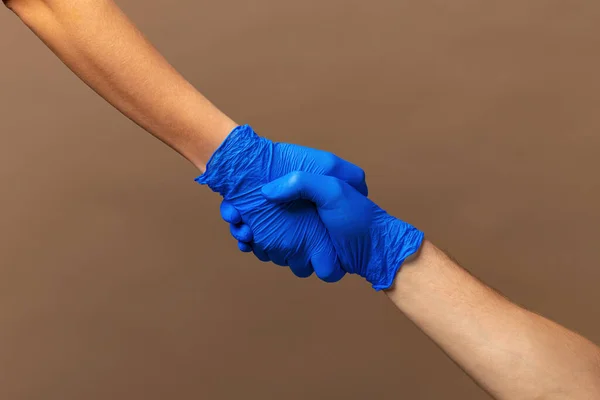 Handshake in a blue gloves, help concept. Personal hygiene during a pandemic — Stock Photo, Image