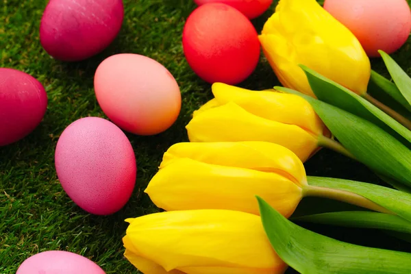 Ovos de Páscoa coloridos na grama decorados com flores — Fotografia de Stock
