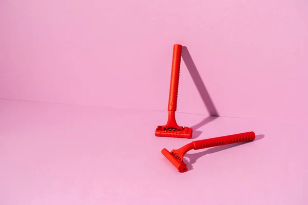 Maquinilla de afeitar desechable rojo sobre fondo rosa, espacio de copia —  Fotos de Stock