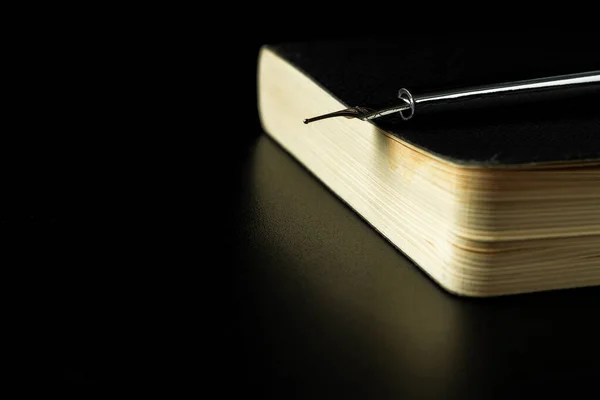 Bloco de notas preto com caneta na mesa preta fechar — Fotografia de Stock