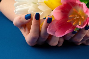 Renkli laleler tutan manikürlü kadın elleri