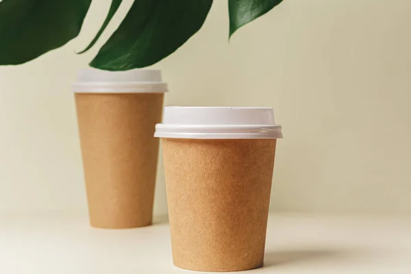 Одноразовая бумажная чашка кофе и зеленый лист — стоковое фото