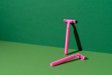 Yeşil arka planda tek kullanımlık jilet, stüdyo çekimi.