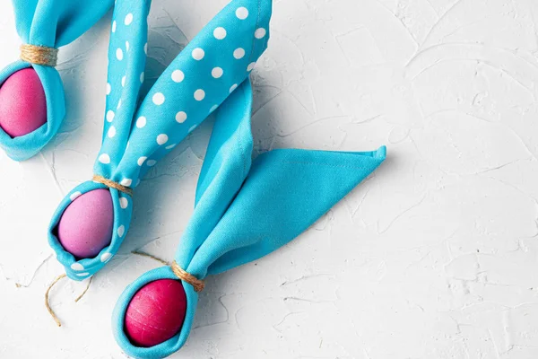 Foto creativa di uova di Pasqua dipinte con orecchie di coniglio fatte di tovagliolo blu — Foto Stock