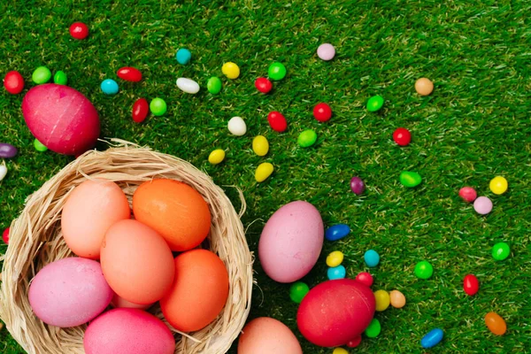 五彩斑斓的鸡蛋和生机勃勃的糖果在草地上.复活节作文 — 图库照片
