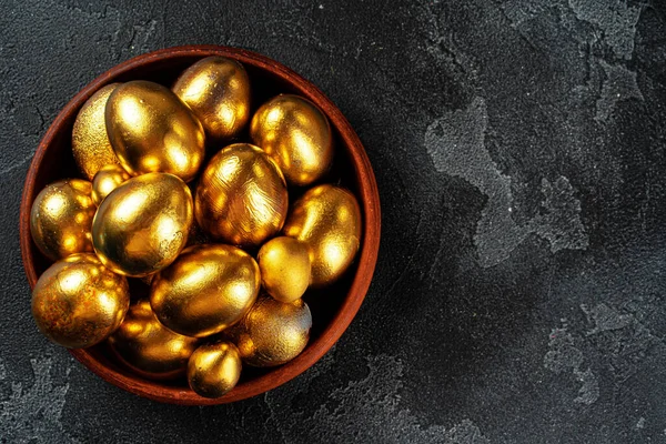 검은 콘크리트 배경 위에 있는 황금빛 부활절 달걀 — 스톡 사진