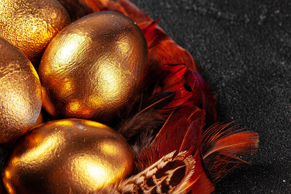 Golden Easter eggs on red bird feathers close up