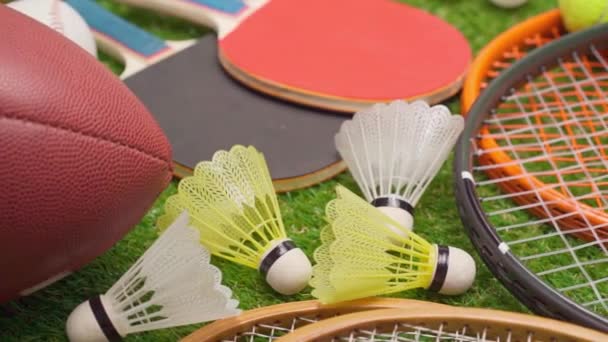 Різні спортивне обладнання на траві, включаючи ракетки, м'ячі, човники і м'яч крупним планом — стокове відео