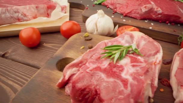 Bistecche fresche di carne cruda su tavola di legno con spezie da vicino — Video Stock