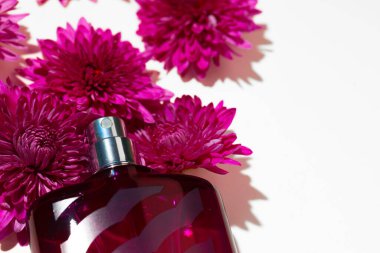 Parfüm spreyi şişesi ve gri arka planda küçük çiçekler.