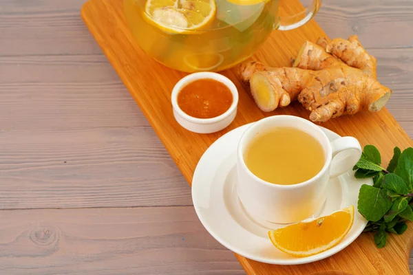 Tasse Tee mit Ingwer und Minze auf Holztisch — Stockfoto