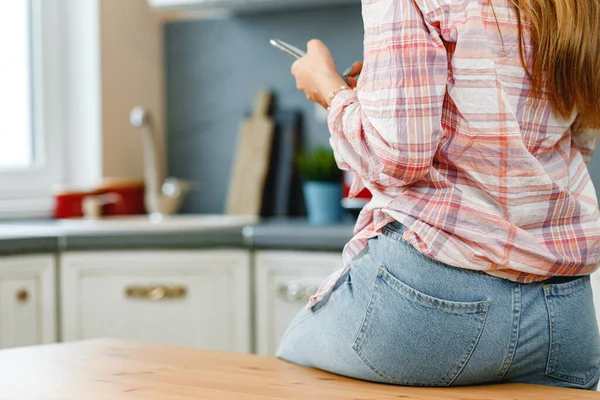 Mulher irreconhecível usando smartphone na cozinha de perto — Fotografia de Stock