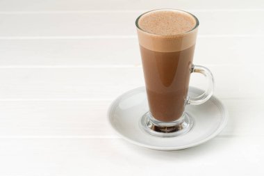 Cam bardak kakao, beyaz ahşap masada içecek.